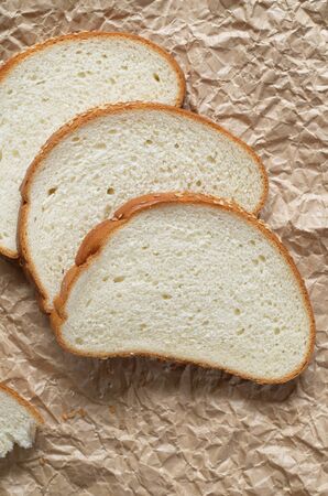 Bread sliced on brown crumpled paper close up, top view