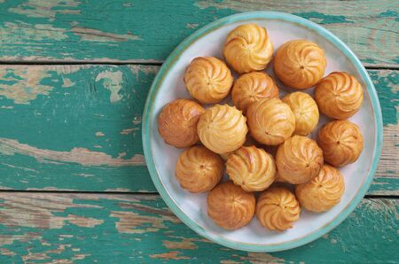 Small Custard Cakes in plate on old green wooden background, top view with copy space