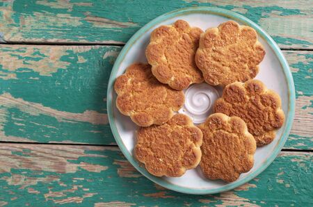 Shortbread cookies on a plate on old green wooden background, top view with copy space