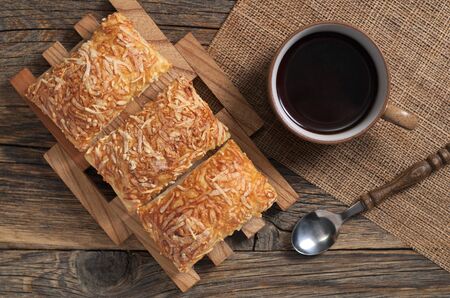 Breakfast with cup of coffee and puff pastry cookies with cheese on rustic table