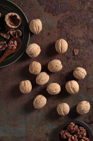 Whole and peeled walnuts on a rusty iron background, top view
