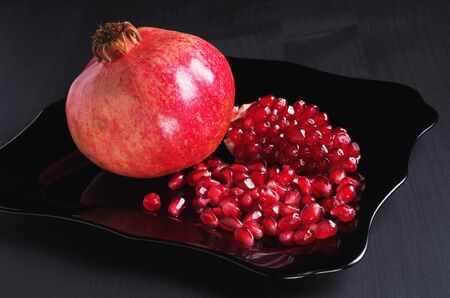 Close-Up of Pomegranate in Plate on Black Tableの写真素材