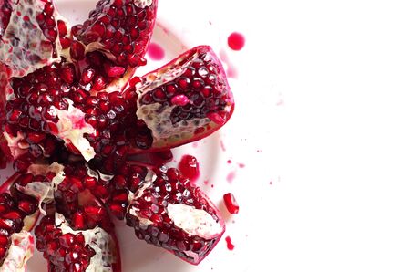 Pomegranate slices in plate on white background, top view with space for textの写真素材