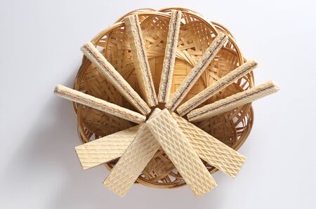 Wafers filling chocolate in wicker wooden plate on a white background, top viewの写真素材