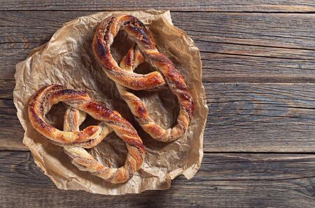 Pretzels with sugar on crumpled paper located on an old wooden background, top view with copy spaceの写真素材