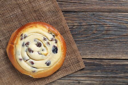 Bun with raisins and cottage cheese filling on old wooden table, top view with copy spaceの写真素材
