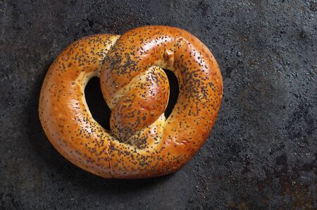 Freshly baked pretzels with poppy seeds on a grunge iron background close-up, top viewの写真素材