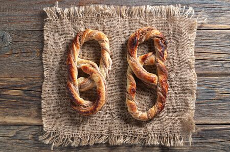 Two sweet pretzels on burlap located on an old wooden background, seen from above