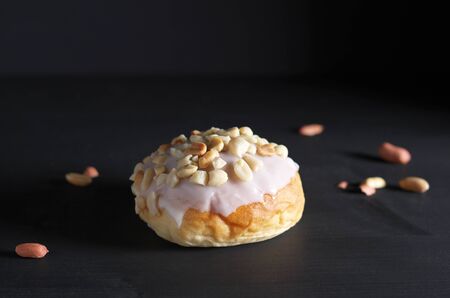 Tasty sweet glazed peanut bun on black tableの写真素材