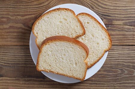 Three slices bread on a plate on wooden background, top view