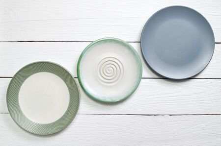 Three empty plate on white wooden table, top view