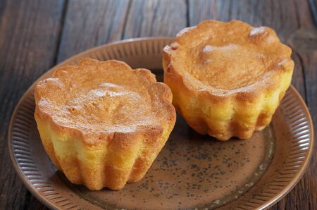 Vanilla cupcakes on a plate on wooden background close-up