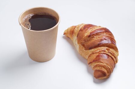 Croissant and paper disposable cup with coffee on white background. Biodegradable dishesの写真素材