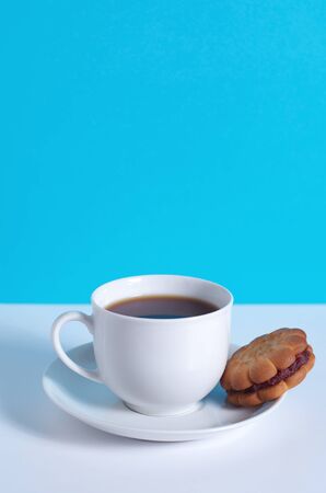 Cup of coffee and cookie on white and blue background. Copy spaceの写真素材