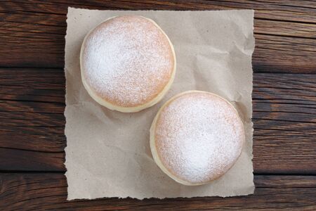 Doughnuts dusted with icing sugar on wooden background, top view