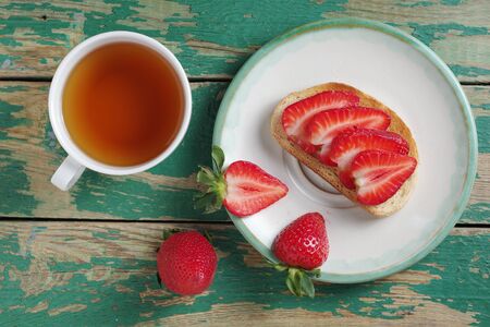 Toast with strawberry and cup of tea on old green wooden background, top viewの写真素材