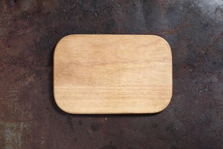 Top view of wooden cutting board on old rusty metal countertop