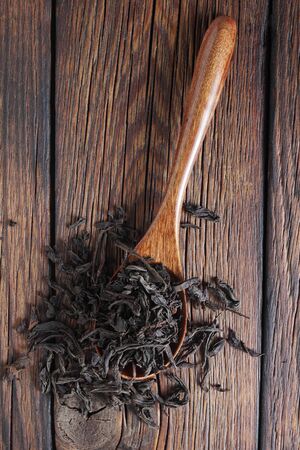 Dry leaf tea on spoon on wooden table close-up, top viewの写真素材