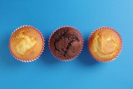 Three fresh cupcakes against blue background, top viewの写真素材