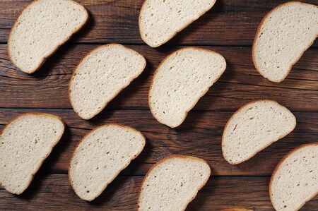 Slices of fresh bread on wooden table as background, top view