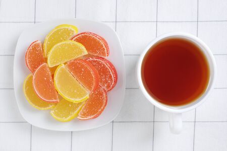 Marmalade in shape of citrus fruits slices and cup of tea on table, top viewの写真素材