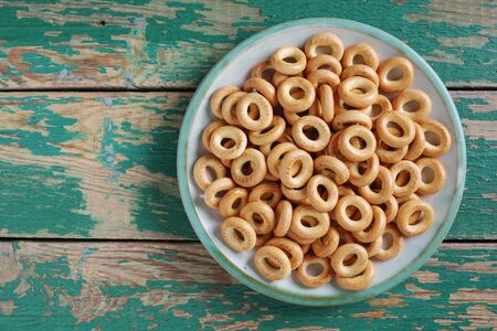 Drying or mini bagels on a plate on old green wooden background, top view with copy space