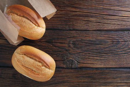 Two loaves of small white bread on wooden background, top view with copy spaceの写真素材