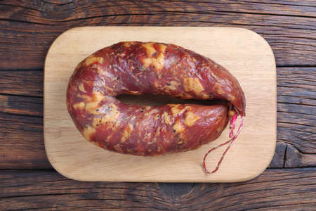 Smoked homemade sausage on a cutting board on a wooden table, top viewの写真素材
