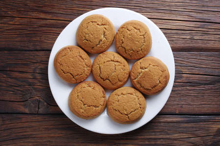 Homemade oatmeal cookies on a plate on wooden background, top view