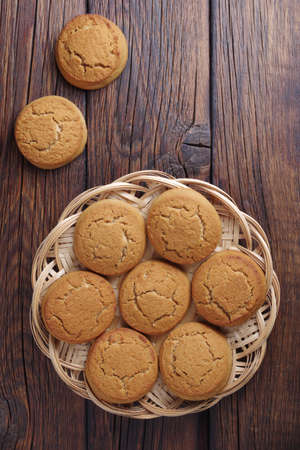 Healthy oatmeal cookies on a wicker wooden plate on wooden background, top view with copy space