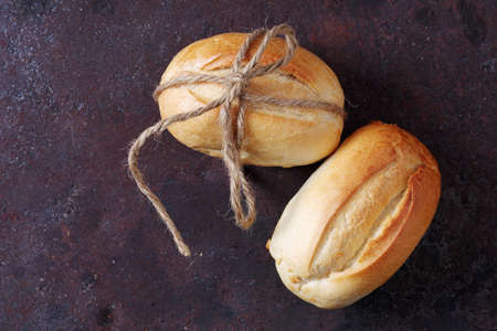 Two loaf of small wheat bread tied with a twine on rusty metal background, top view