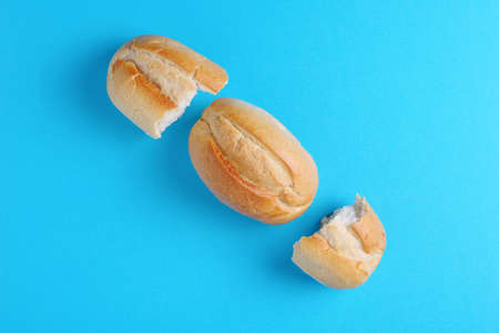 Loaves of bread whole and two half on blue background, top view