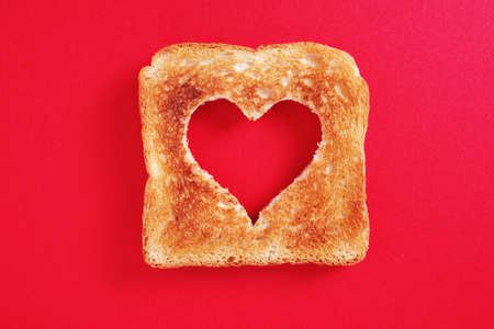 Fried toasted bread with a heart-shaped cut on two-tone background, top view with copy spaceの写真素材
