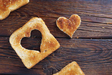 Toast bread with a heart-shaped cutout on wooden background, top viewの写真素材