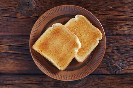 Two toast on a plate on wooden background, top viewの写真素材
