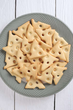 Dry cracker cookies in plate on white wooden table, top view