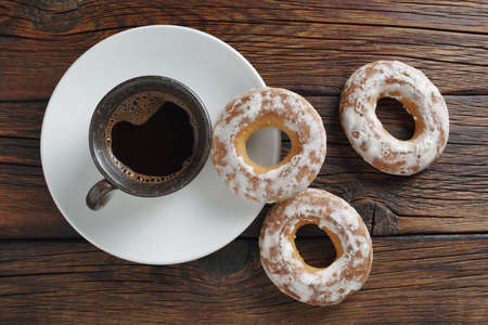 Cup of coffee and glazed bagels on wooden background, top viewの写真素材