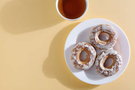 Glazed bagels and cup of tea on light background, top viewの写真素材