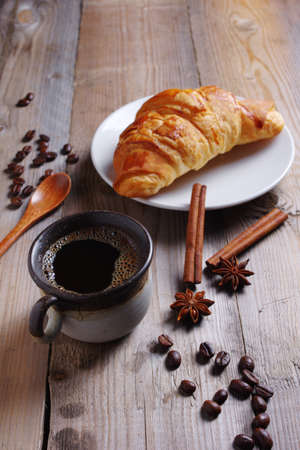 Croissant and cup of coffee on old wooden tableの写真素材