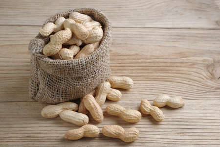 Peanuts in shack and near on wooden background