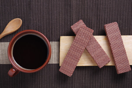 Chocolate wafers with filling and cup of coffee for breakfast on the table, top viewの写真素材