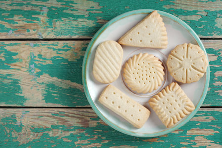 Various shortbread cookies on a plate on old green wooden background, top view with copy spaceの写真素材