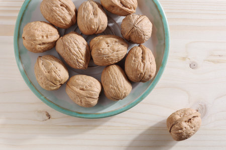 Walnuts on a plate on wooden table, top viewの写真素材