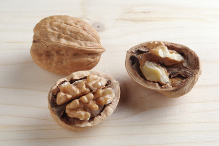 Tasty cracked walnuts on wooden background close up