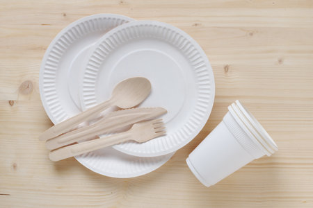 Disposable tableware and cutlery on wooden background, top viewの写真素材