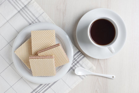 Wafers with filling and cup of coffee for breakfast on the table, top view