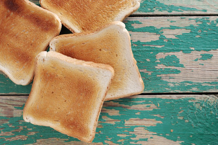 Slices of toasted bread on old green wooden table, top view with copy space