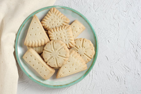 Various shortbread cookies on a plate on light background, top view with copy space
