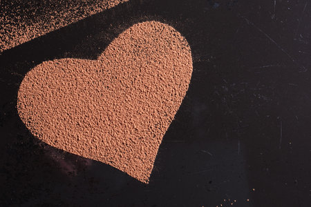 Heart shaped chocolate or cocoa on an old black metal sheet, top viewの写真素材