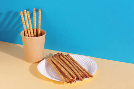 Crispy bred straw with seeds in disposable paper tableware on yellow-blue backgroundの写真素材